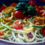 Zucchini Noodles Recipe in a bowl with herbs and cheese, fresh and simple low carb vegan pasta.